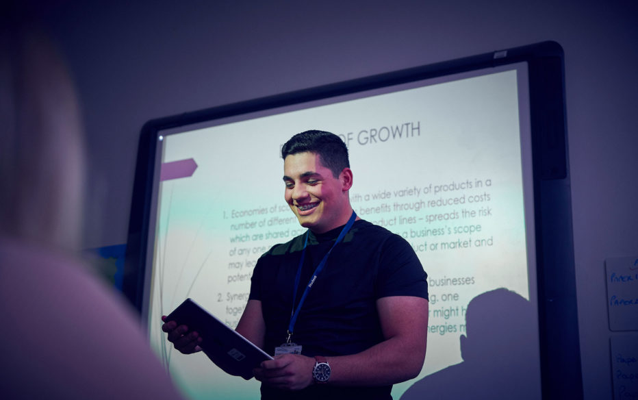 A Sunderland College business studnet delivering a presentation in front of a projector